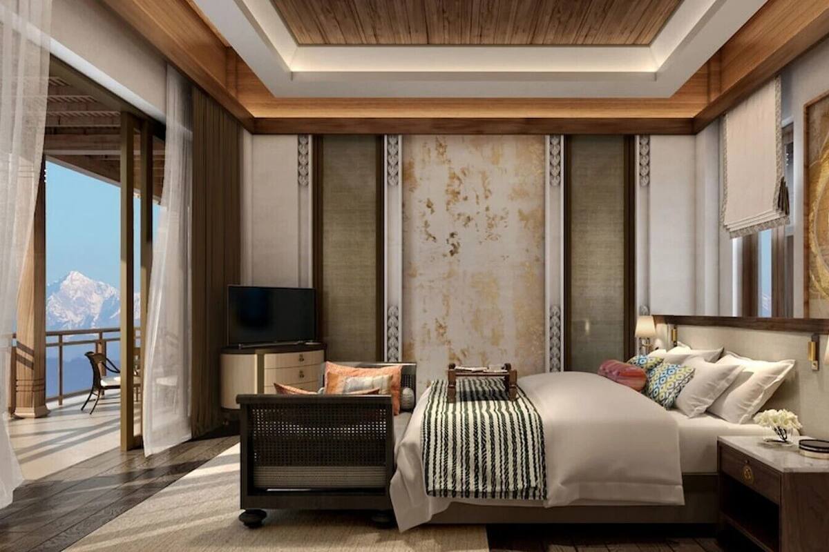 Habitación de hotel moderna con una cama grande, televisión, escritorio y vista a la montaña.