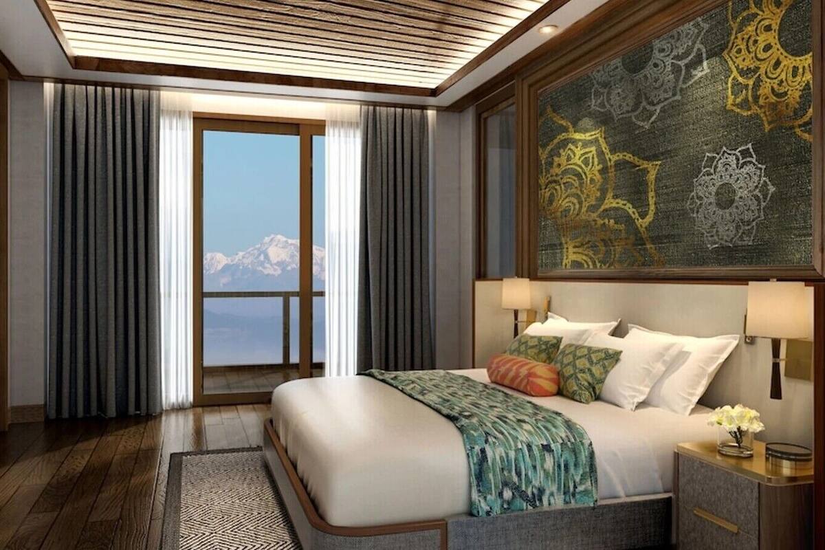 Habitación de hotel con cama, televisión, escritorio y ventana grande con vista a la montaña.