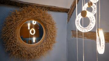 A circular mirror with a straw-like border, a wooden beam, and hanging light fixtures.