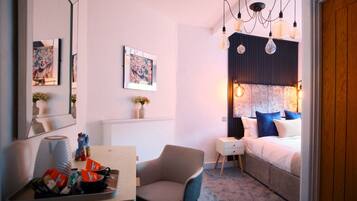 A modern bedroom with a bed, bedside table, chair, and artwork on the walls.