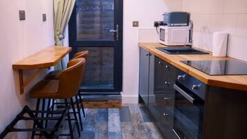Une cuisine compacte avec un coin repas, un four à micro-ondes et une vue à travers une porte vitrée.