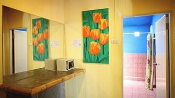 Een kamer met een houten bureau, een magnetron en een schilderij van oranje tulpen aan de muur.