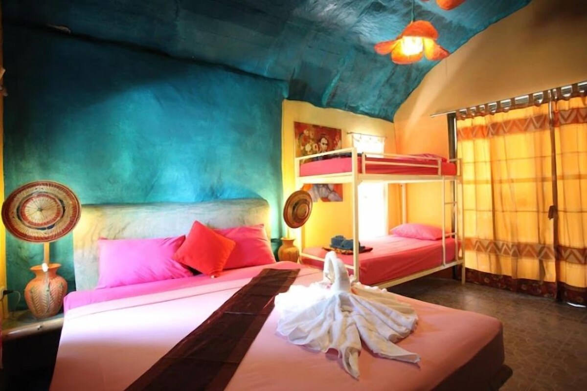 A room with a bunk bed, a bedside table with a lamp, a wall clock, and a window with curtains.