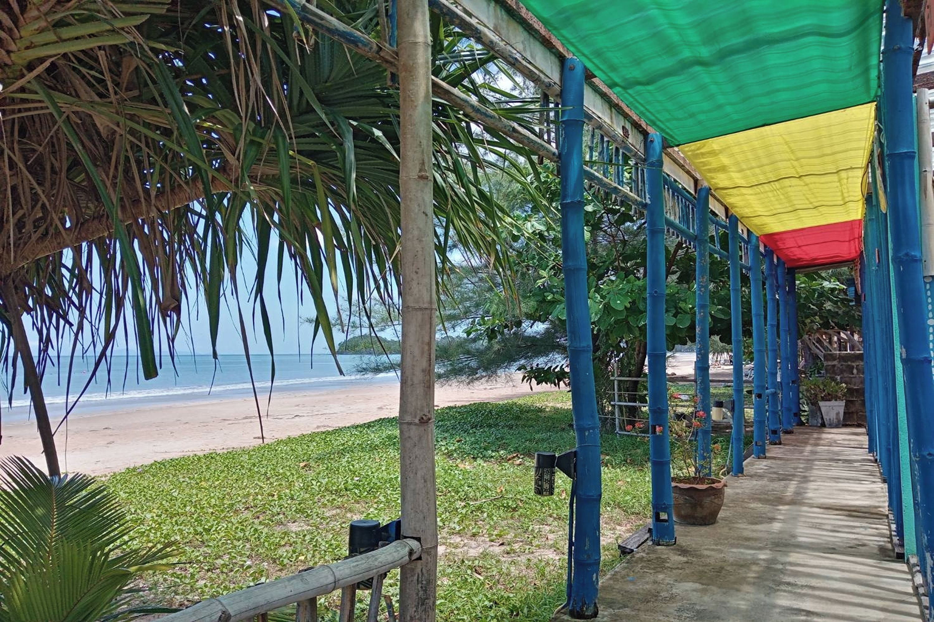 A covered walkway with blue pillars and a green, yellow, and red canopy.