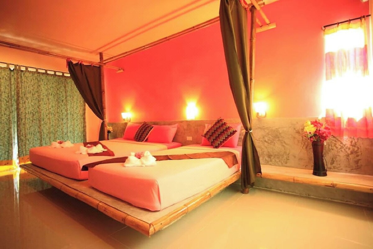 Quarto com uma cama grande, uma mesinha e um vaso de flores.