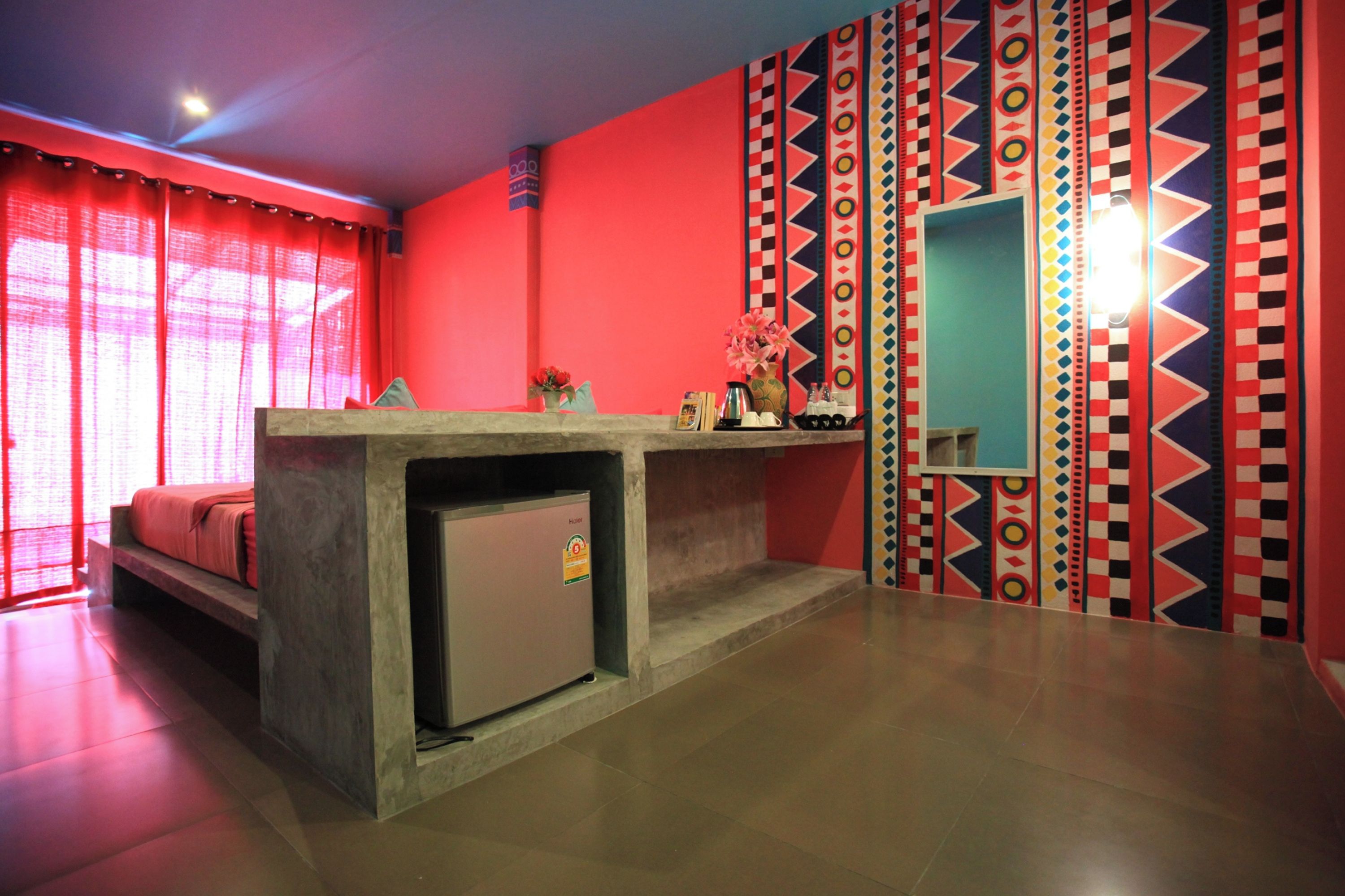 Una habitación con cama, un refrigerador pequeño, una encimera y un espejo.