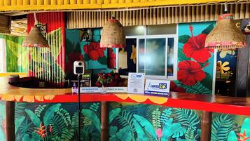 A reception area with a vibrant tropical mural, a check-in counter, and a sign indicating a 'LANTAN OF OK' service.