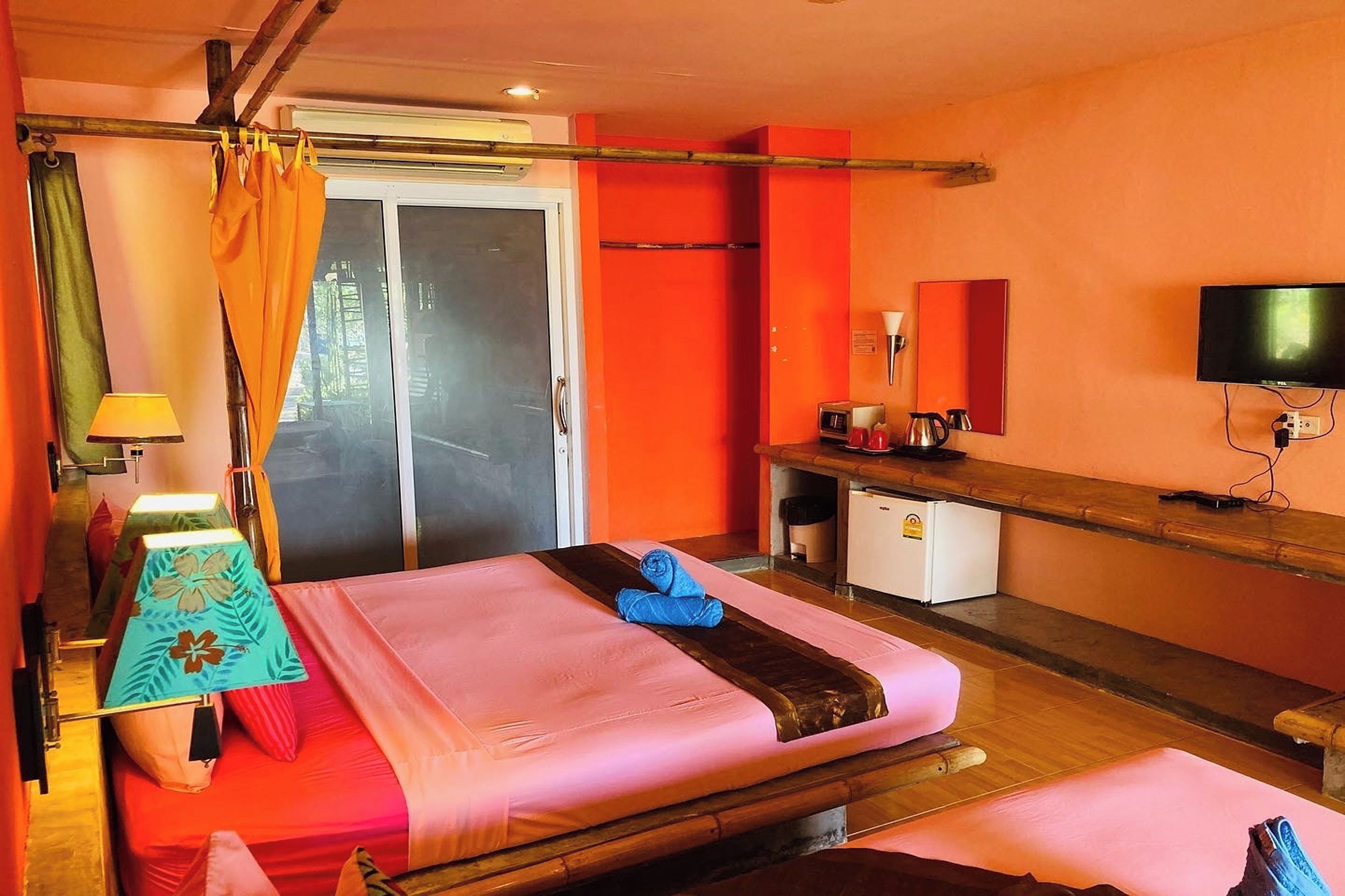 A hotel room with a bed, a desk, a television, and a sliding door.