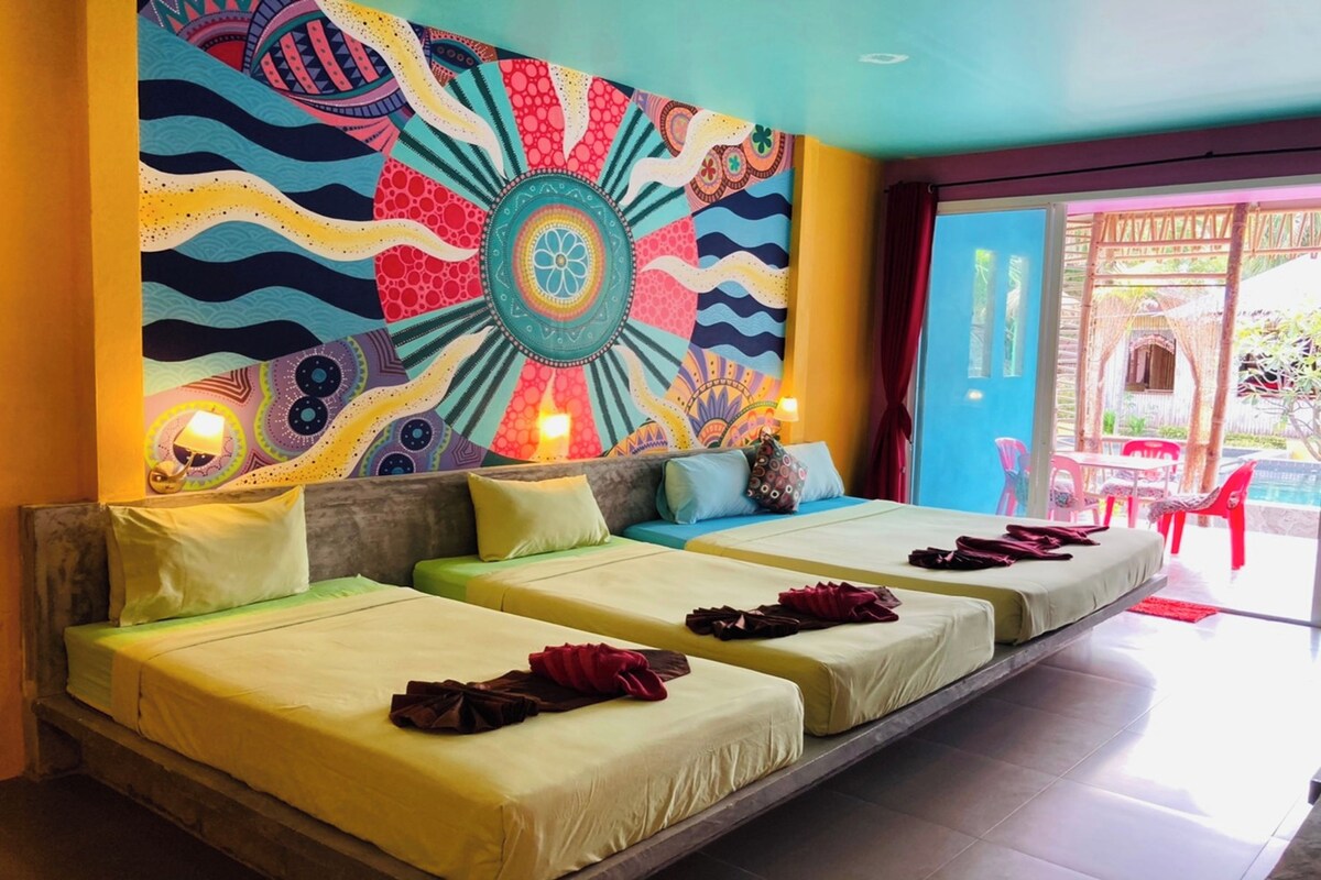 Una habitación con un mural colorido, un sofá cama y vistas al exterior.