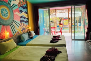 Une chambre d’hôtel avec deux lits, une tapisserie murale aux couleurs vives et une vue sur l’espace extérieur.
