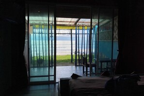 Una habitación con un amplio ventanal corredera que da a un balcón con vista al mar.