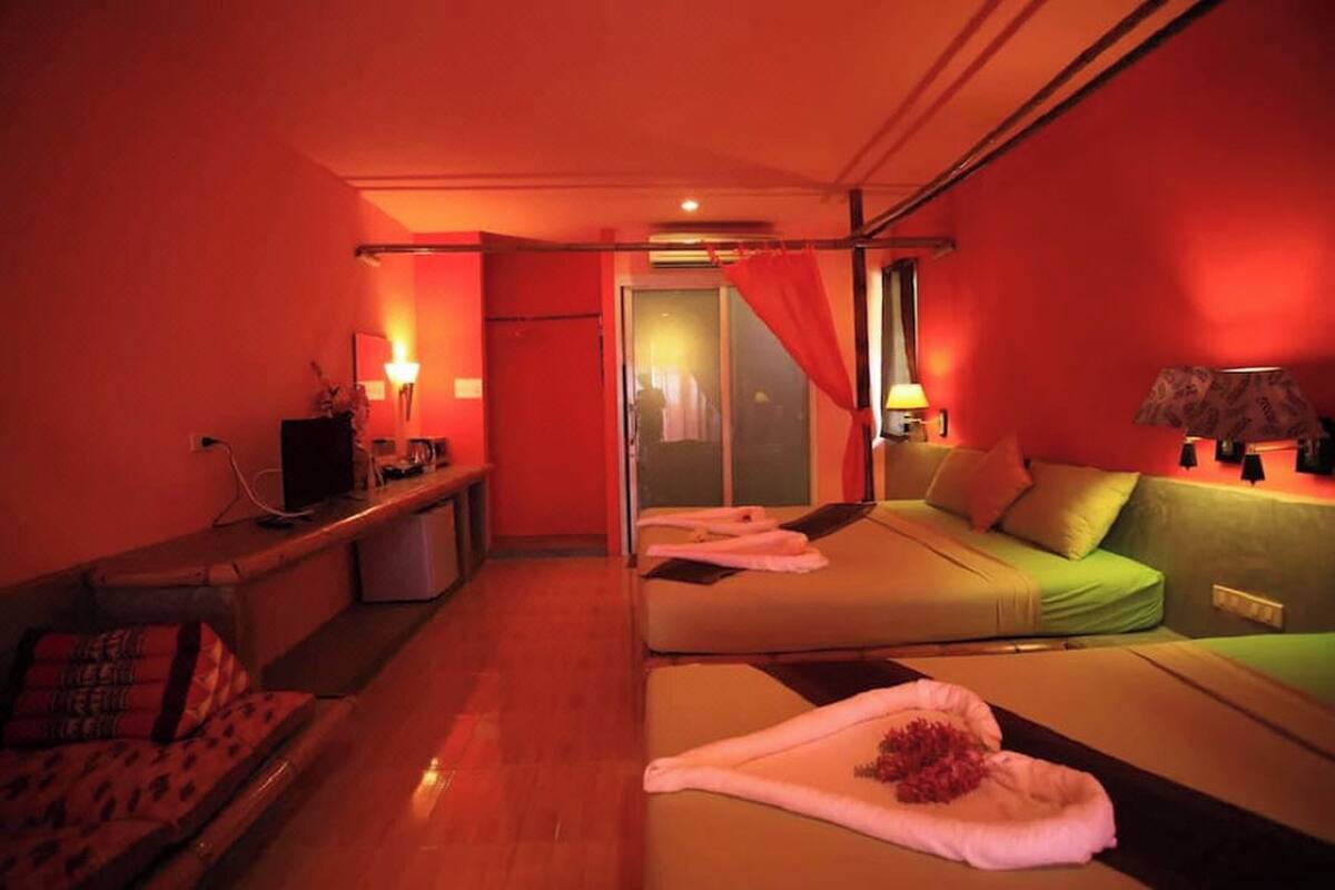 Habitación de hotel con dos camas, un sofá, un televisor y un espejo.