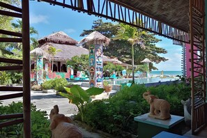 Un resort con edificios de techo de paja, piscina y vegetación tropical.