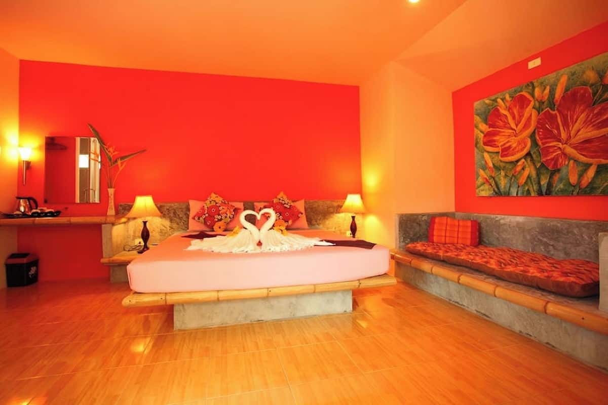 Una habitación de hotel con una cama grande, un banco y un cuadro en la pared.