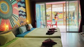 Una habitación de hotel con dos camas, un mural colorido y vistas al área exterior.
