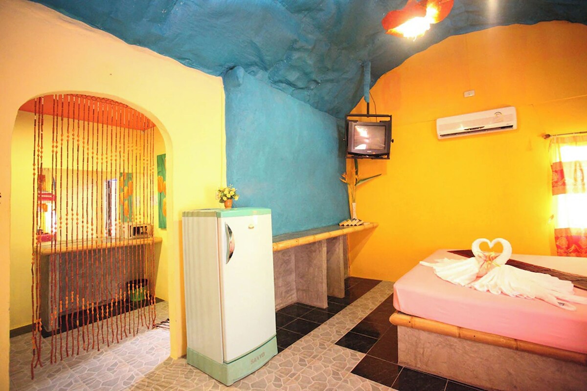 Una habitación con cama, un refrigerador pequeño, televisión y baño con cortina de ducha.