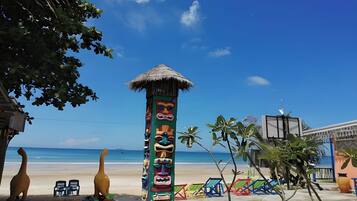 A beach scene with a decorated totem pole, beach chairs, and a small hut.