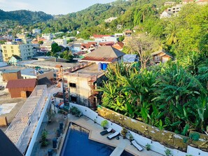 A residential area with a swimming pool, buildings, and lush greenery. - Oceanview Treasure Hotel And Residence (Patong)