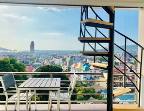 A balcony with a view of a cityscape, including buildings and a distant mountain. - Oceanview Treasure Hotel And Residence (Patong)