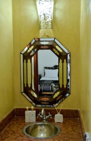 A bathroom with a hexagonal mirror, a sink, and toiletries. - Casa De Marrakech Riad Guest House (Marrakech)