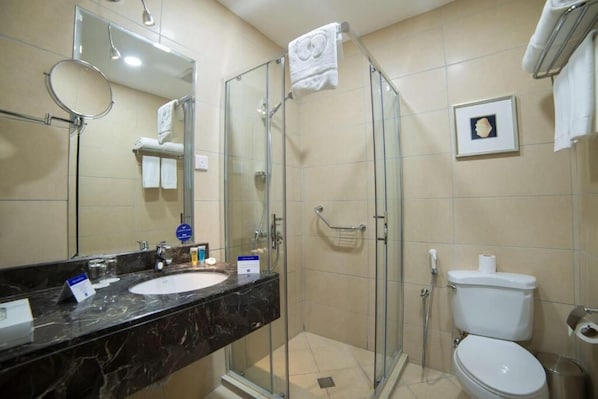 Une salle de bain avec une douche à parois de verre, un lavabo et des toilettes.