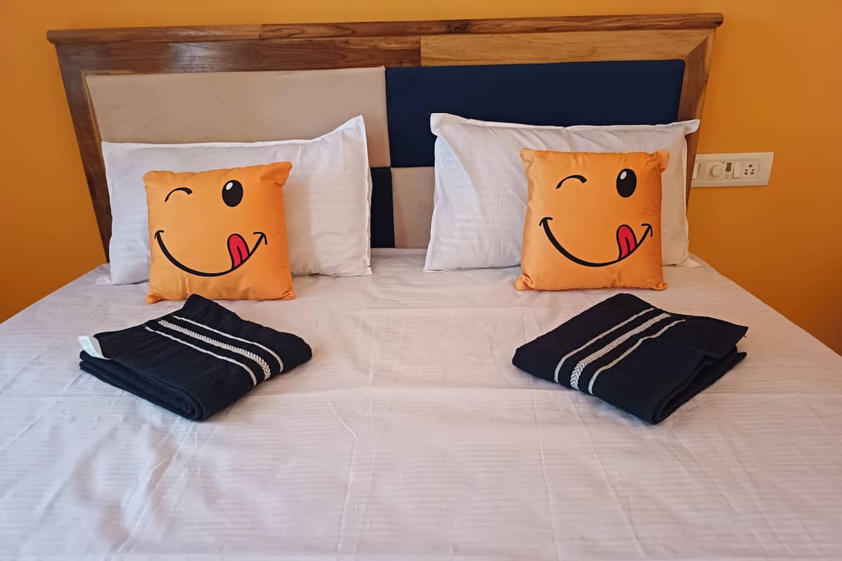 A bed with two pillows, two folded towels, and a wooden headboard.