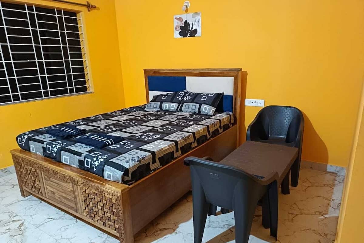 A room with a bed, a wooden chest, a desk, and a chair.