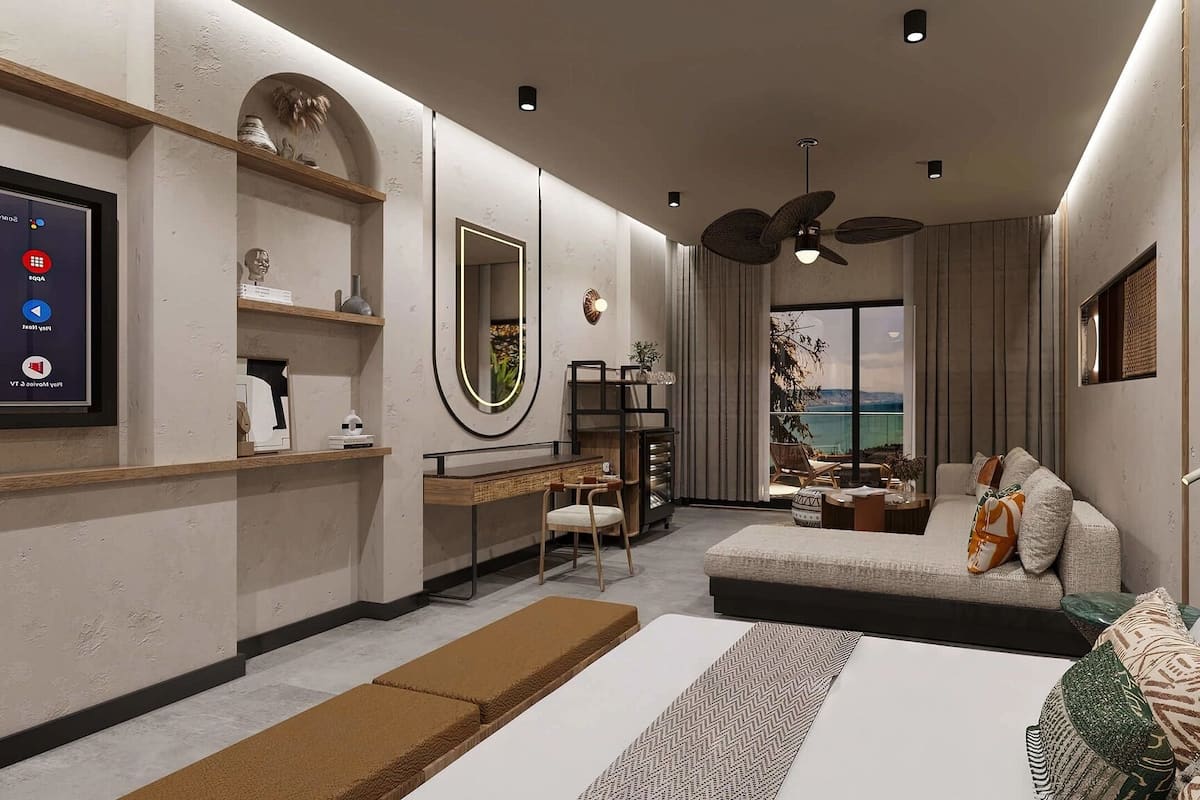 A modern bedroom with a bed, a desk, a chair, a sofa, a large mirror, and a view of the sea.