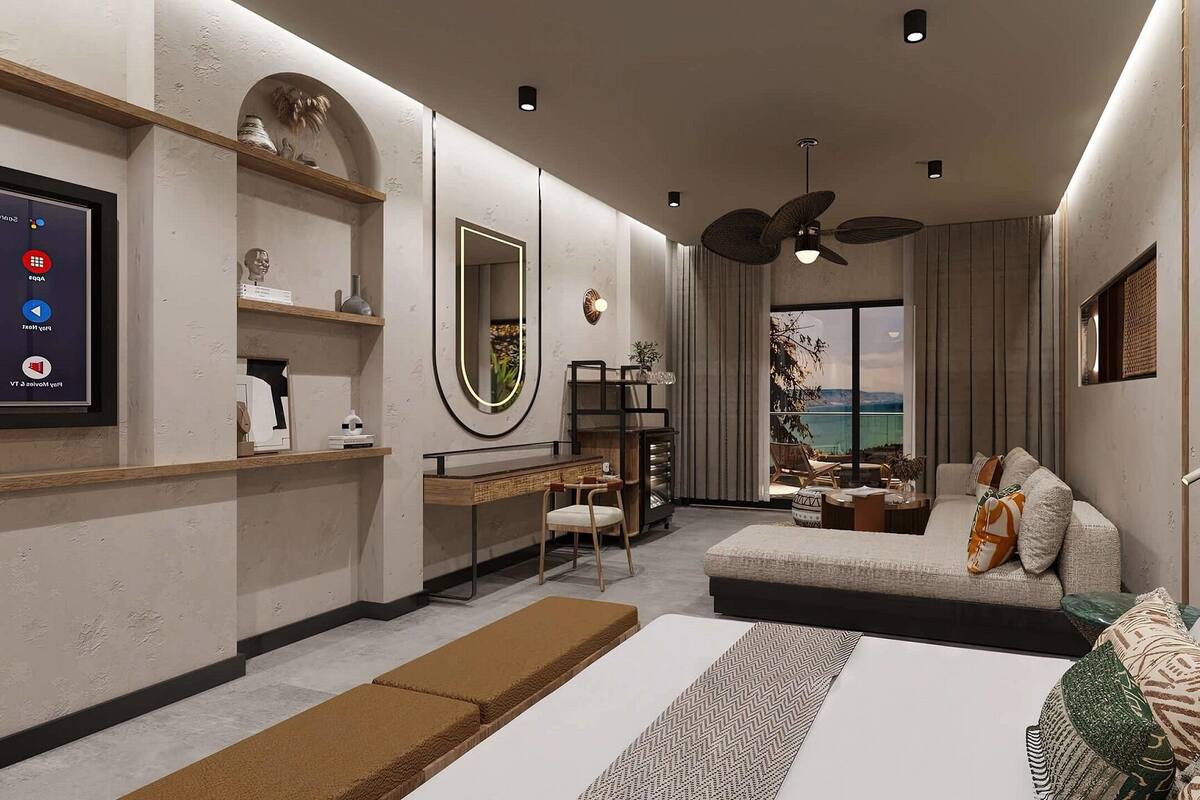 A modern bedroom with a bed, a desk, a chair, a sofa, a large mirror, and a view of the sea.