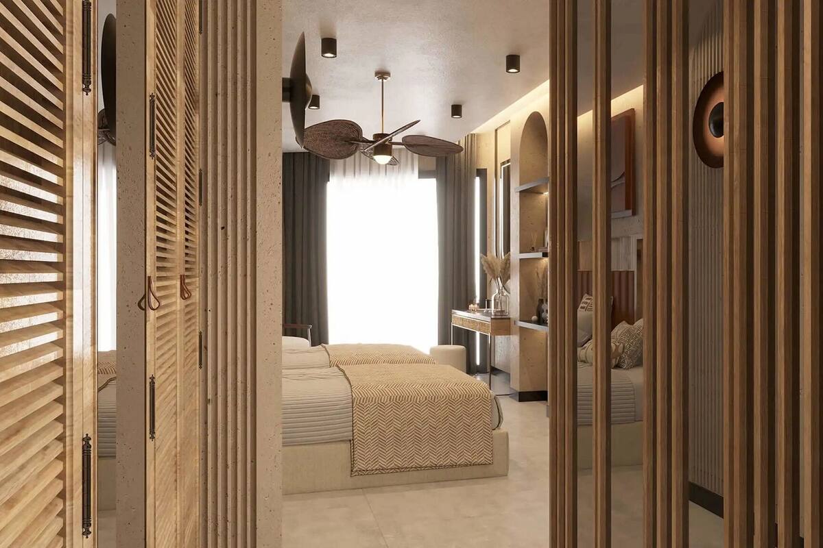 A walk-in closet with wooden slat doors, a bed with a patterned bedspread, a ceiling fan, and a mirror.