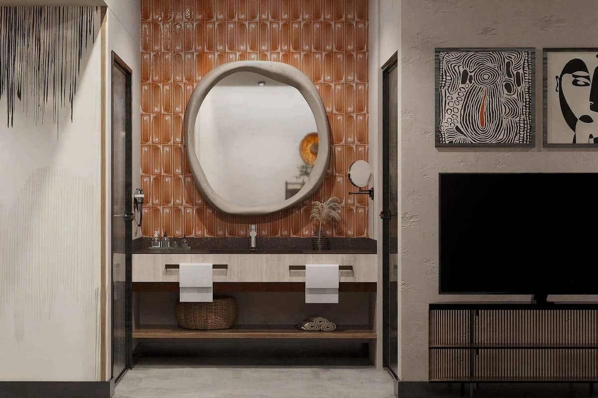 A modern bathroom with a wooden vanity, a round mirror, and a flat-screen TV mounted on the wall.