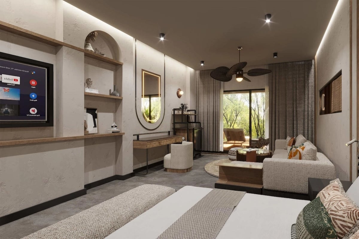 A modern bedroom with a large bed, a seating area, a TV, and a view of the outdoors.