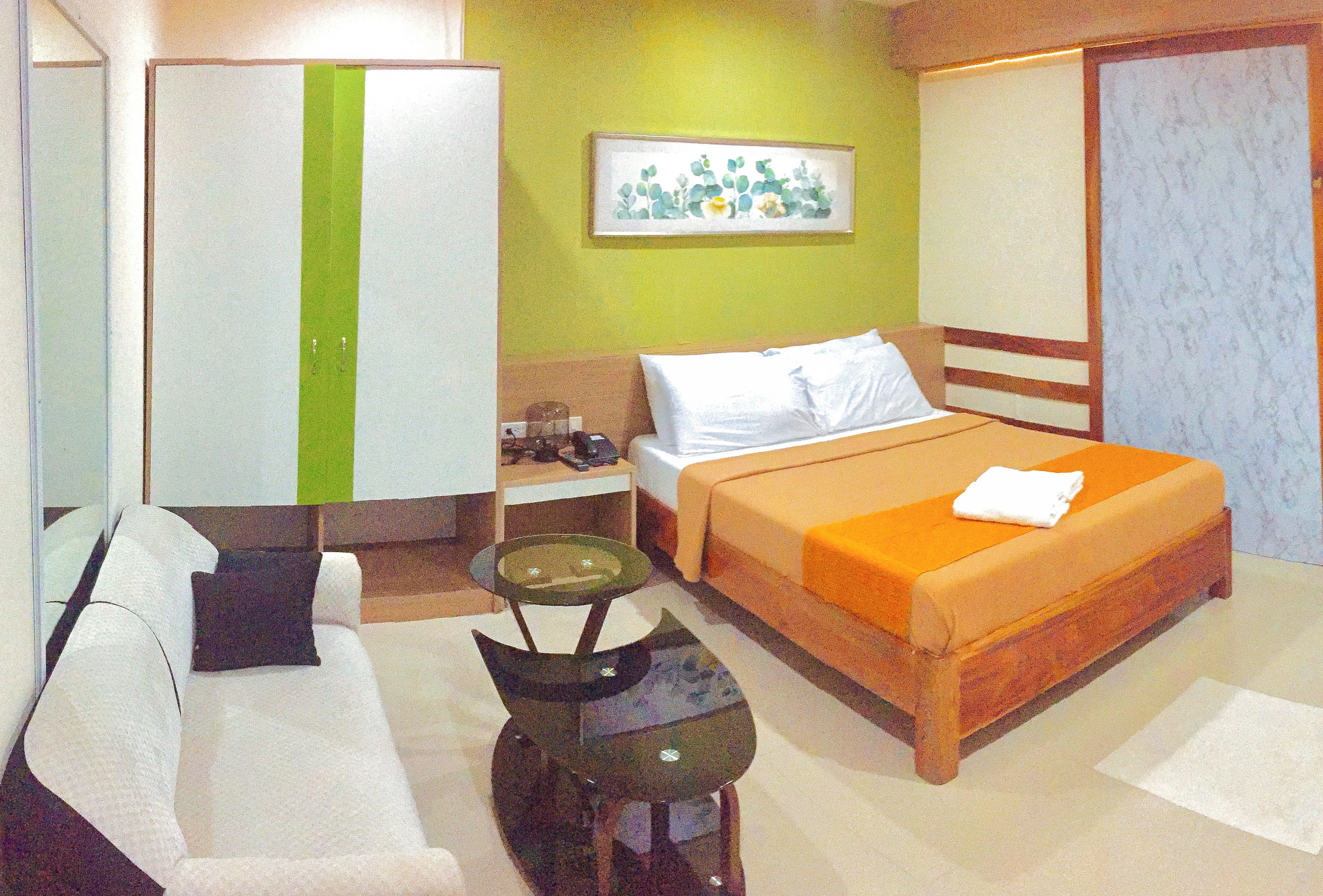 Habitación de hotel con cama, sofá, escritorio, armario y una mesita.