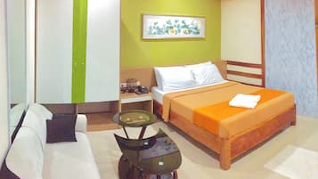 Habitación de hotel con cama, sofá, escritorio, armario y una mesita.