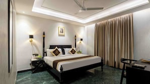 A hotel room with a bed, bedside lamps, a desk, and a ceiling fan. - Foxoso Hotel Delhi Airport (New Delhi)