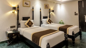 A hotel room with two beds, a ceiling fan, wall-mounted lamps, and a green marble floor. - Foxoso Hotel Delhi Airport (New Delhi)