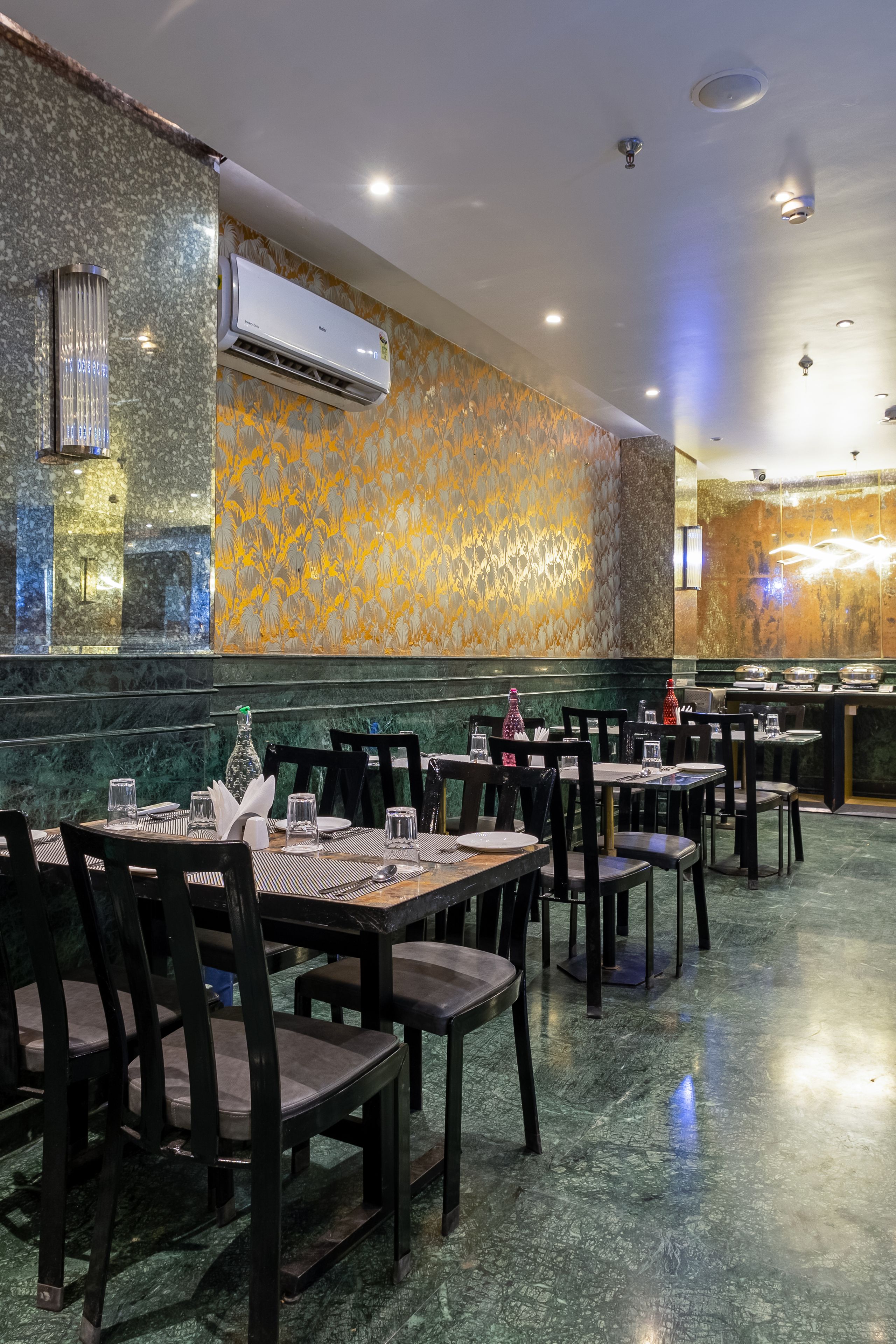 A restaurant with marble walls, air conditioning, and tables set for dining.