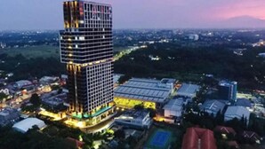 A high-rise hotel with a modern design, surrounded by a cityscape and a sports court. - The Cozy Rooms At The Ayoma Residence Bsd, Serpong (South Tangerang)