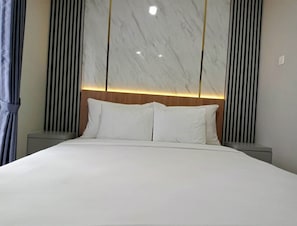 A modern hotel room with a large bed, wooden headboard, and vertical striped curtains.
