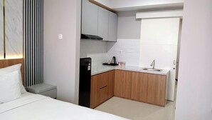 A modern hotel room with a bed, a small kitchenette, and a bathroom. - The Cozy Rooms At The Ayoma Residence Bsd, Serpong (South Tangerang)