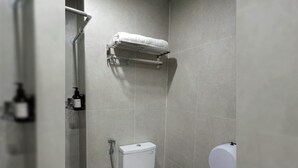 A modern bathroom with a toilet, a shower, and a towel rack. - The Cozy Rooms At The Ayoma Residence Bsd, Serpong (South Tangerang)