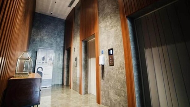 A modern hallway with wooden paneling, a marble floor, and an elevator. - The Cozy Rooms At The Ayoma Residence Bsd, Serpong (South Tangerang)