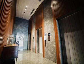 A modern hallway with wooden paneling, a marble floor, and an elevator. - The Cozy Rooms At The Ayoma Residence Bsd, Serpong (South Tangerang)