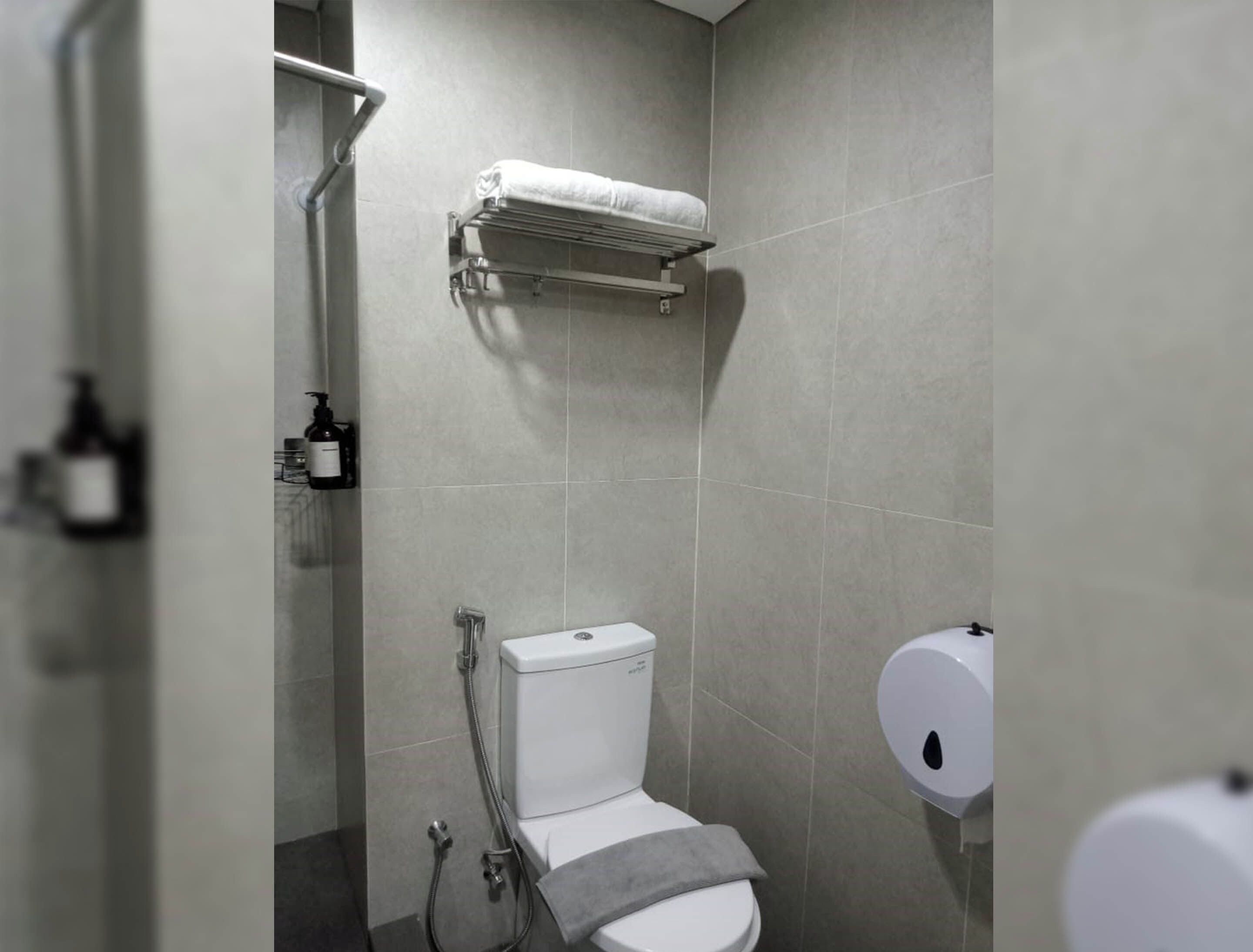 A modern bathroom with a toilet, a shower, and a towel rack.