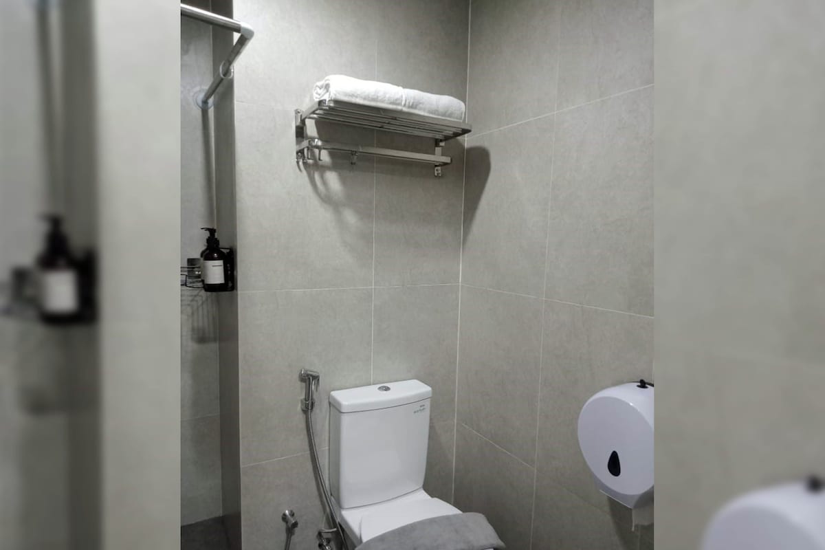 A modern bathroom with a toilet, a shower, and a towel rack.