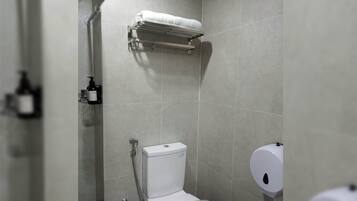 A modern bathroom with a toilet, a shower, and a towel rack.