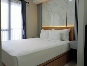 A modern hotel room with a large bed, a wooden headboard, and a marble accent wall.