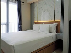 A modern hotel room with a large bed, a wooden headboard, and a marble accent wall. - The Cozy Rooms At The Ayoma Residence Bsd, Serpong (South Tangerang)