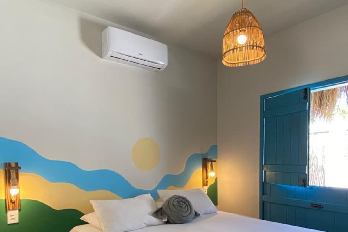 A bedroom with a bed, an air conditioner, a hanging light fixture, and a wall mural.