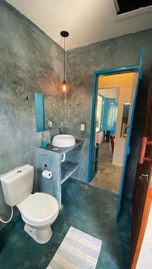 Een badkamer met toilet, wastafel en spiegel.